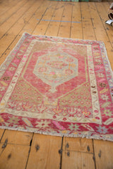 Distressed vintage Oushak rug: geometric patterns in blush, aubergine, slate blue, and ivory.