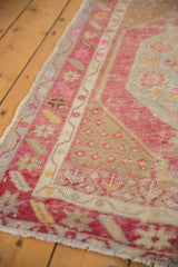 Distressed Oushak rug's worn pile, with red, ivory, and blue geometric patterns.