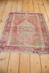 Distressed Oushak rug's lower border with pink, blue, ivory geometric motifs and fringe.