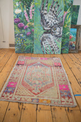 Distressed Oushak rug end corner, showing geometric spandrel, vibrant pinks, blues, and red.