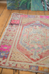 Distressed Oushak rug pile worn to foundation, with geometric pink, gold, blue motifs.