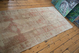 Corner of distressed Oushak runner showing faded geometric patterns and worn pile.