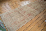 Distressed Oushak runner corner with even wear, featuring faded ivory and pale red tones.