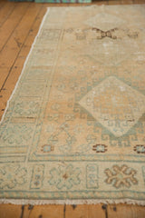 Distressed vintage Oushak runner's aged texture, showing pale beige, blue, and brown floral patterns.