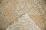 Distressed Oushak rug corner: worn pile texture, fringe, and exposed hand-knotted foundation.