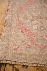 Distressed Oushak rug corner, with blush geometric motif, original selvage, and fringe.
