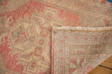 Distressed blush and ivory Oushak rug detail showing low pile, hand-knotted reverse, and fringe.