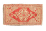 Distressed vintage Oushak rug mat, central diamond medallion, red and beige geometric patterns.