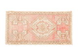 Distressed vintage Oushak rug mat with a pink serrated medallion and pale tones, 1'7