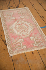 Intact selvage, worn fringe, and distressed pile of a vintage blush pink Oushak rug corner.