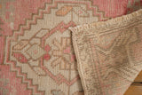 Vintage distressed Oushak rug's hand-knotted foundation revealed alongside its worn pink pile.