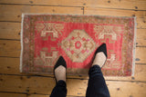 Distressed Oushak rug close-up showing faded blush, geometric plant motifs, and oxidized silver border.