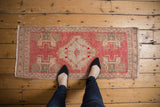 Distressed vintage Oushak rug showing serrated pink medallion and low pile.