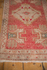 Distressed pink and ivory low pile with geometric patterns and fringe.