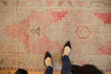 Distressed vintage Oushak runner with faded blush and ivory stepped geometric patterns.
