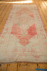 Blush and ivory vintage distressed Oushak rug with stepped medallion showing faint foundation.