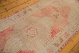 Distressed blush and ivory Oushak runner border with meandering vine and palmette motifs.
