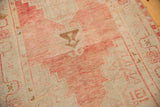 Distressed vintage Oushak rug featuring blush field with stepped pattern and visible worn texture.