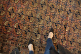 Chestnut brown and navy floral guls on a vintage Turkmen carpet with plant-like border.