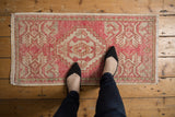 Distressed vintage Oushak rug with blush pink medallion, ivory field, and even wear.