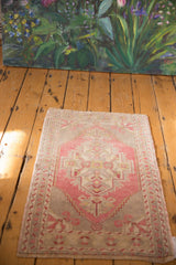 Distressed Oushak rug corner with blush, ivory geometric pinwheel motif and low pile.