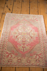 Distressed vintage Oushak rug corner with blush, ivory hues and ram's horn motif.