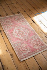 Distressed Oushak rug corner with pale pink, ivory plant motifs and secured fringe.