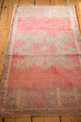 Distressed vintage Oushak rug end, showing bubblegum pink plant motifs and low pile texture.