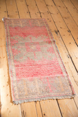 Fringe and distressed low pile texture of a pink and silver Oushak runner end.