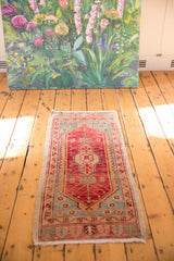 Distressed texture of a vintage Oushak runner with cherry red and aqua blue patterns.