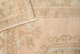 Distressed blush pink pile and muted patterns, showing subtle foundation and fringed edge.
