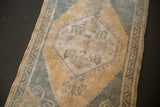 Distressed Oushak rug detail: pale blue, ochre rams head motif, secure side selvage.