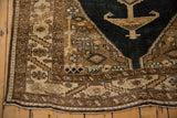Distressed corner of vintage Northwest Persian rug, featuring serrated leaf border in bronze and sand.