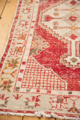 Distressed cherry red field with worn pile, ivory serrated corner pattern on Oushak rug.
