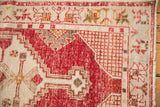 Worn cherry red and antique ivory stepped patterns on a vintage Oushak rug corner.