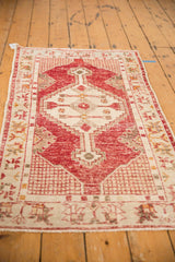 Distressed cherry red Oushak field with geometric grid and antique ivory border motifs.