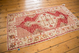Corner of distressed Oushak runner showing cherry red serrated field design and ivory border.