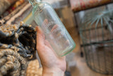 Embossed R. Boehmer and Sons Mount Kisco on a light blue antique glass bottle.