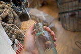 Embossed Boehmer lettering on the side of a light blue antique glass bottle.