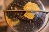 Black globe surface with visible paper expansion and peeling.