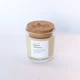 Merry + Bright soy candle in glass jar with branded cork lid and white label.