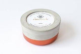 Scented soy candle in a cylindrical concrete vessel with a copper base.