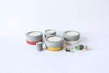 A collection of concrete soy candles in various sizes with copper, gold, and white color-dipped bases.