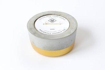 Round gold-dipped concrete scented soy candle with a white product label.