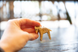 Hand holding vintage wooden zebra ornament, highlighting its hand-painted stripes.
