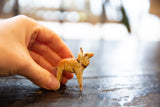 Vintage wooden deer ornament held by fingers, showing hand-painted detail and aged finish.