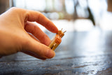 Close-up of vintage wooden deer ornament's hand-painted side, held by fingers.