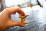 Delicate base of vintage hand-painted wooden deer ornament held by hand.