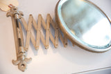 Extended accordion arm of the antique fleur de lis shaving mirror with distressed white paint.