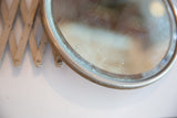 Patina on the round metal frame and aged surface of the antique mirror.